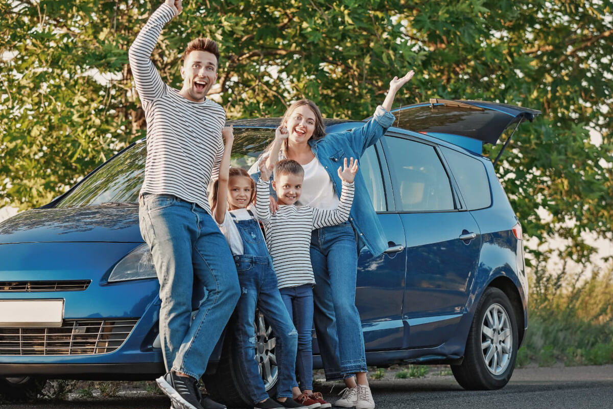 車をバックに笑顔で写真を撮る家族