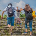 子どもの腕を掴んで階段を登る親子